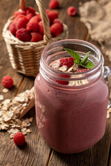 Smoothie with raspberry, oatmeal and mint in a jar on rustic wooden background.