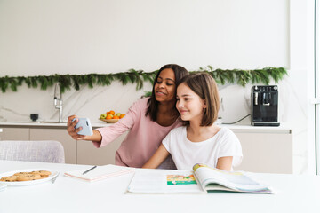 Obraz na płótnie Canvas Multiracial sisters taking selfie photo while doing homework together