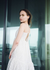 City portrait of beautiful young woman in white dress.