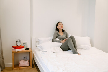 Young asian girl with phone sitting on the bed