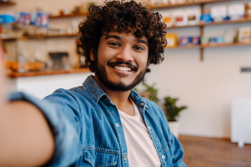 Selfie of young smiling handsome curly indian man