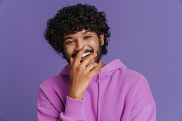Fototapeta na wymiar Portrait of young indian handsome curly laughing man covering mouth