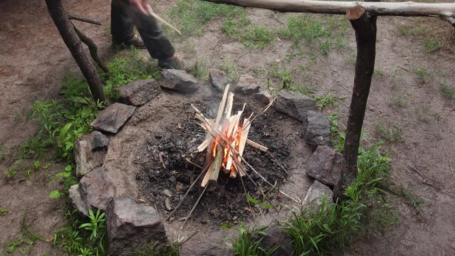 Arranging bonfire outdoors. 4k stock video footage of firewood for cooking food over open fire. Travel and hiking concept
