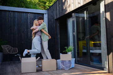 Cheerful young couple moving in their new tiny house in woods. Conception of moving and sustainable living.