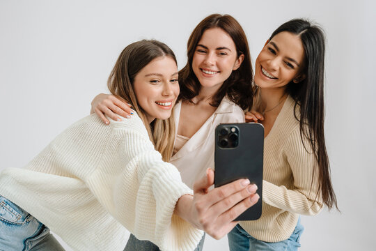 Three beautiful brunette women smiling and taking selfie photo