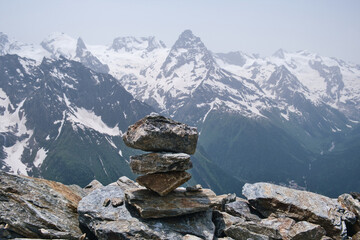 Stack of stones on top of the mountain against a background of mountain snow peaks. Concept of equilibrium, balance and harmony.