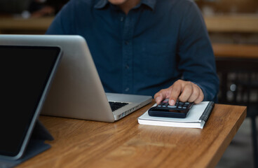 Hand Male doing finances and calculate on desk about cost at home office in the morning.