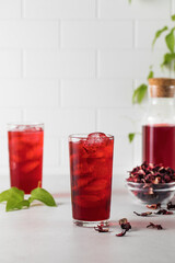 A refreshing drink made of dried hibiscus leaves and ice in a glass.