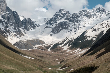 Fototapeta na wymiar Georgia, Caucasus Mountains, Juta valley - cold river, blue sky, mountain from stones and snowy peak Chaukhebi in summer.
