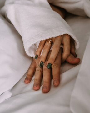 Female and male hands under blanket in bed