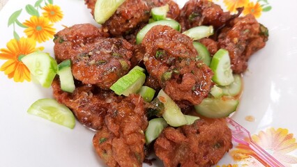 Deep fried fish balls with sweet and sour sauce and cucumber on a white floral plate. Delicious, Thai street food.