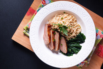 Asian food concept homemade organic Alkaline noodles with duck roasted on wooden board with black background with copy space