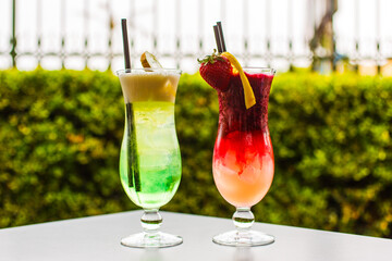 Due cocktail analcolici alla frutta di colore verde e rosso serviti in un bar con snack salati per aperitivo