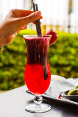 Cocktail analcolico rosso alla fragola mentre viene mescolato da un cliente con una cannuccia di...