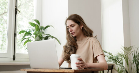 Young woman tired having meeting online. Student using laptop computer at home. Working, studying,...