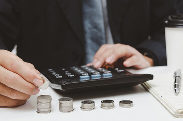 businessman person hand holding coin stack money and calculator on desk.business finance tax growth investment accounting insurance concept