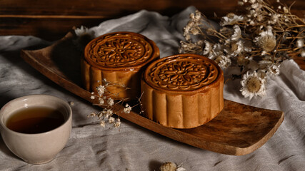 Chinese mooncakes with cup of tea and decorating with dried flower on wooden table for Mid Autumn festival