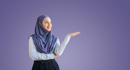 Portrait of a young muslim woman isolated on purple background, welcome or recommend concept.