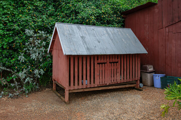 Red wooden chicken coop in farm yard background