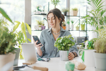 Woman taking care of her plants and using her smartphone