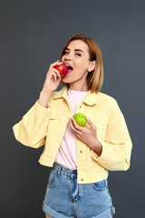 smiling blonde woman holding green and red apples