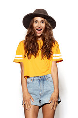 Stylish portrait of happy girl in casual trendy outfit. Pretty cheerful woman wearing jean shorts and bright orange shirt posing on white background. Fashion and lifestyle concept