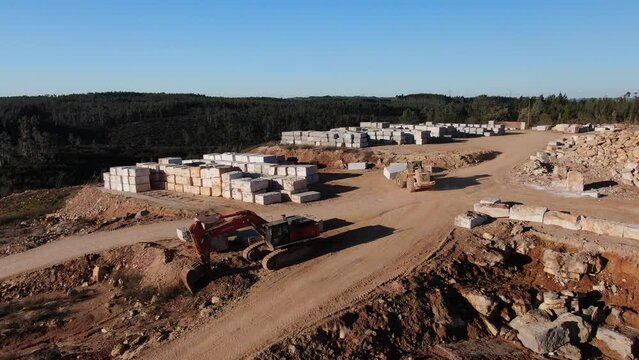 Excavadora trabajando en una mina de m&aacute;rmol transportando un bloque