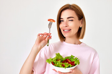beautiful woman eating fresh vegetable salad on white background
