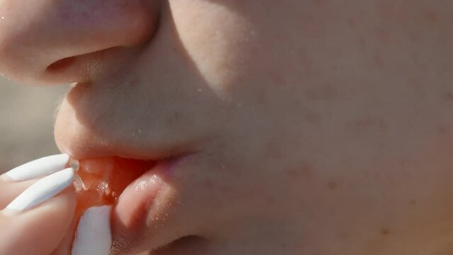Girl on the beach puts a piece of watermelon in her mouth close-up, Slow mo
