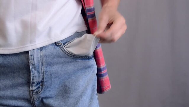 A woman's hand looks for money in an empty pocket and then turns it out. The concept of no money. Poverty