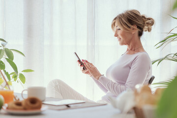 Mature woman using her smartphone at home