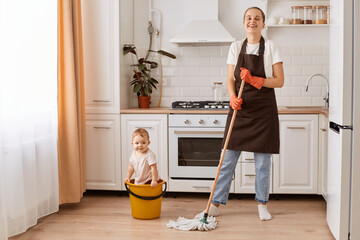 Full length shot of cheerful cheery housewife making fast domestic work wiping floor in kitchen,...