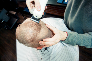 Naklejka premium A barber's hand is trimming hair on the top of male's head.