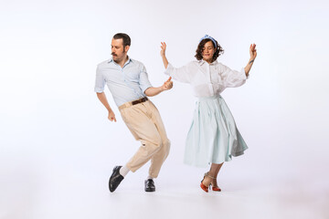 Portrait of young cheerful couple, man and woman, dancing isolated over white studio background. Disco party