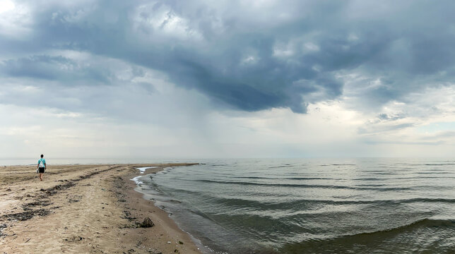 A lonely silhouette of a man under thunderclouds over the wild coast of cape Kolka. Cape Kolka - the meeting place of the Baltic sea and the Gulf of Riga, Latvia.