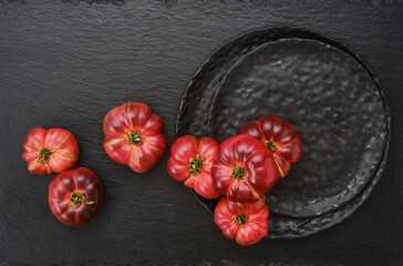 The harvest of assorted tomatoes in a black plates and black slate surface. Tomatoes different...