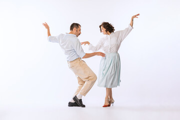 Portrait of young beautiful couple, man and woman, dancing isolated over white studio background....