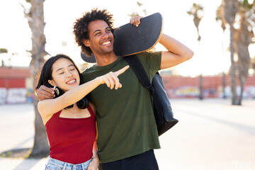 Boyfriend and girlfriend enjoy outside. Happy couple with skateboard having fun.