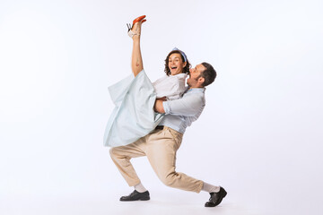 Portrait of beautiful couple, man and woman, dancing over white studio background. Recreation of...