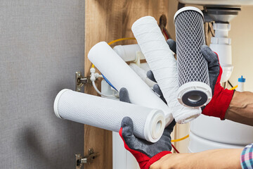 Water filter cartridge in human hand. Plumber hands holding cartridge for replace water filter at...