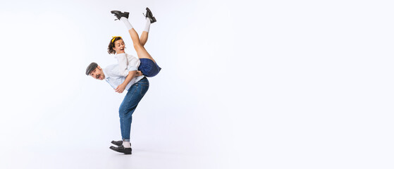 Portrait of young cheerful couple, man and woman, in stylish retro outfit dancing isolated over...