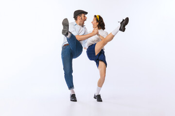 Portrait of young emotive couple, man and woman, dancing boogie woogie isolated over white studio...