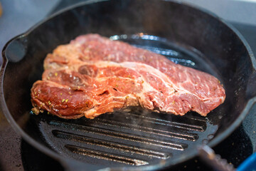 Shot of cooking barbecue beef steak on a hot grill in kitchen at home.