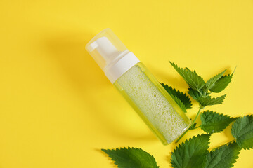 Natural cosmetics with nettle leaves. Lotion, cream, shampoo in mock up bottles, skin care and hair treatment.
