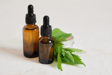 Glass dropper bottle of nettle oil or serum and nettle leaves