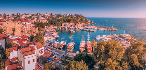 Naklejka premium Aerial sunset view of the picturesque harbor with marina port with cruise tourist ships near the old town of Kaleici in Antalya. Turkish Riviera and resort paradise