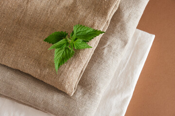 nettle leaves and stack of natural fabrics on brown background
