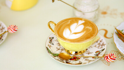 Banner with an elegant yellow cup of coffee with cream and a pattern. Good morning. Breakfast concept.Copy space on the left