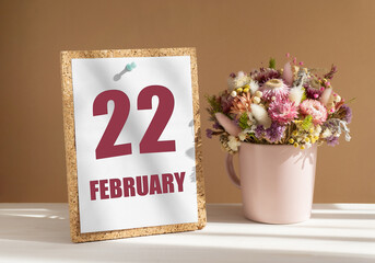 february 22. 22th day of month, calendar date.Bouquet of dead wood in pink mug on desktop.Cork board with calendar sheet on white-beige background. Concept of day of year, time planner, winter month