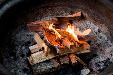 Starting a campfire in a firepit with kindling. Camping lifestyle. - obrazy, fototapety, plakaty